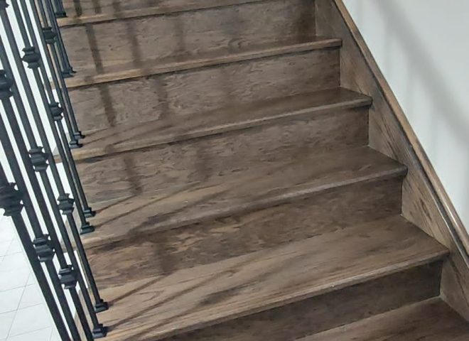 Staircase renovated with sleek modern metal pickets and rich wood staining, creating a timeless and luxurious look.